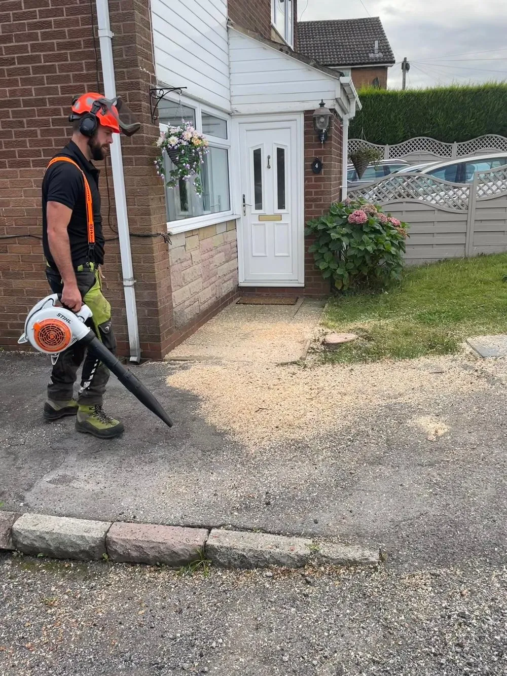 A man with a chainsaw standing in front of a house.