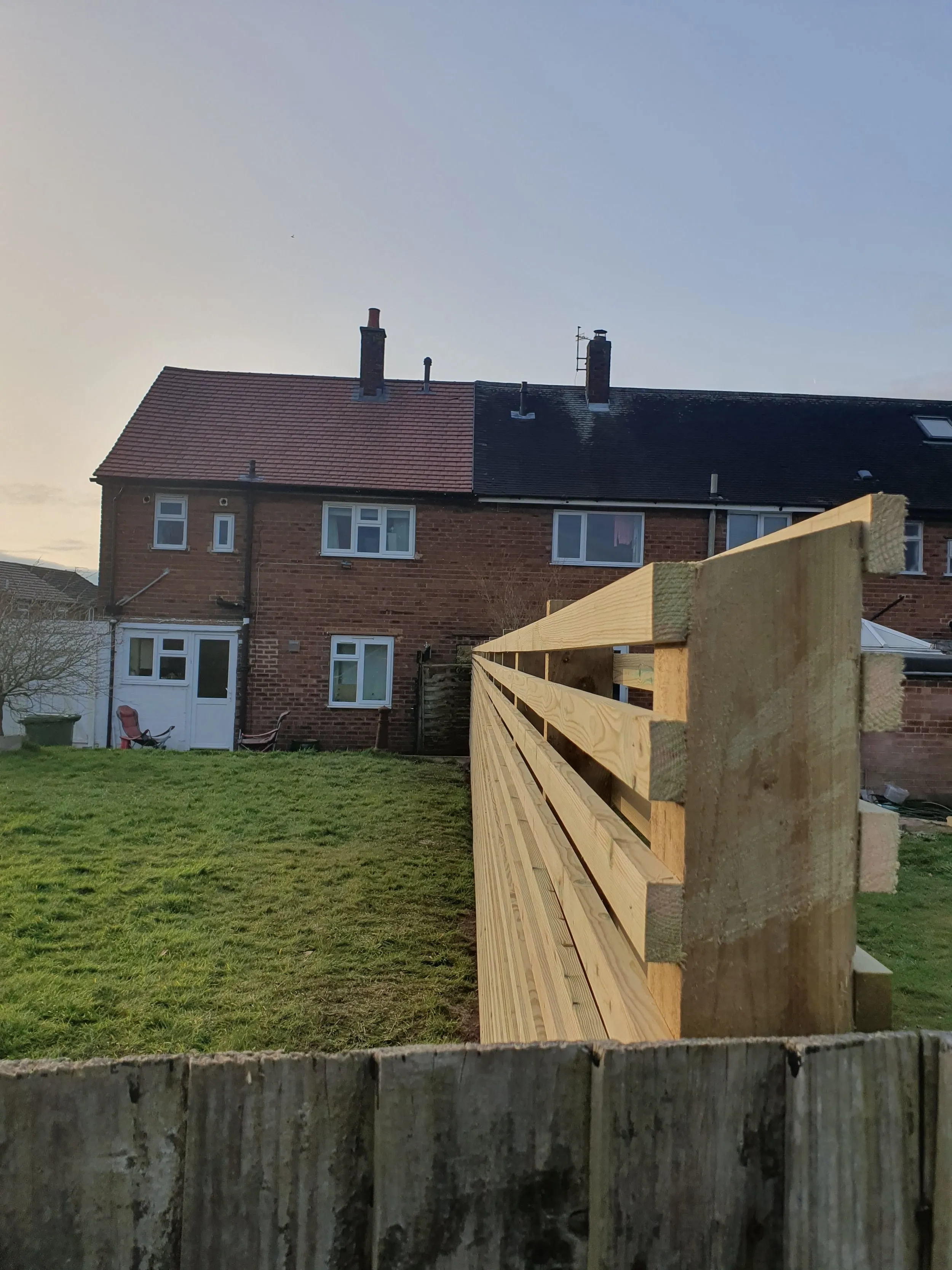 A wooden fence in front of a brick house.