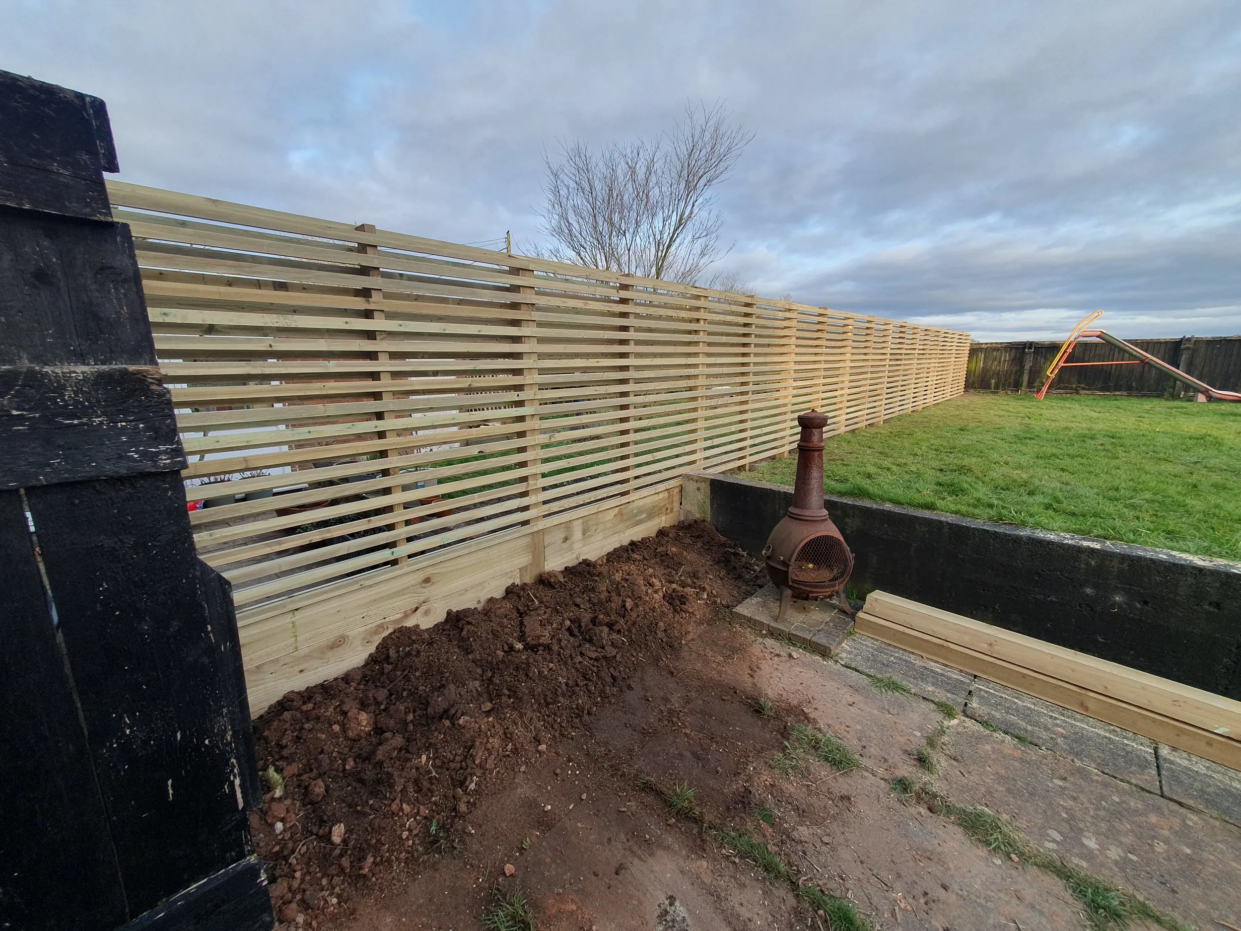 A wooden fence with a pipe sticking out of it.
