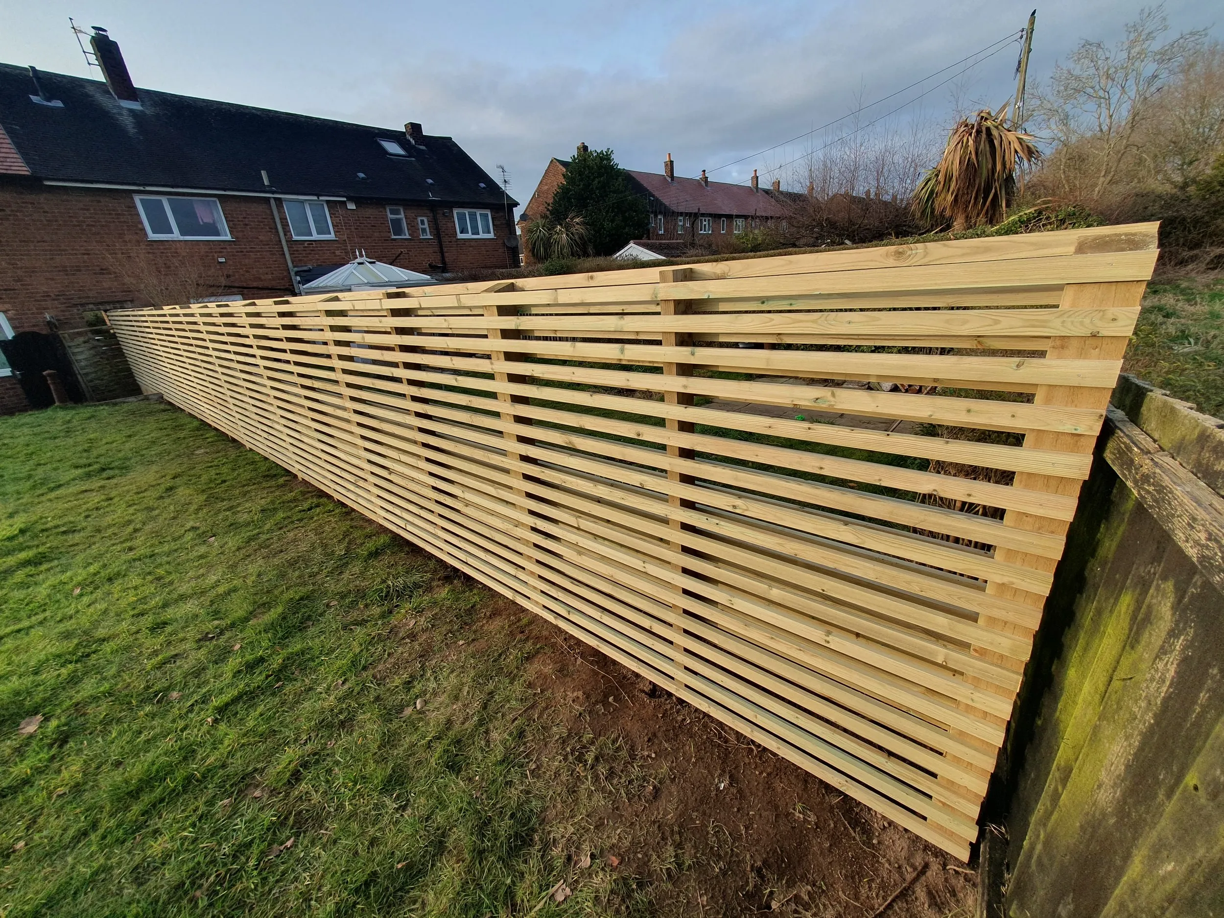 A wooden fence in a yard next to a house.