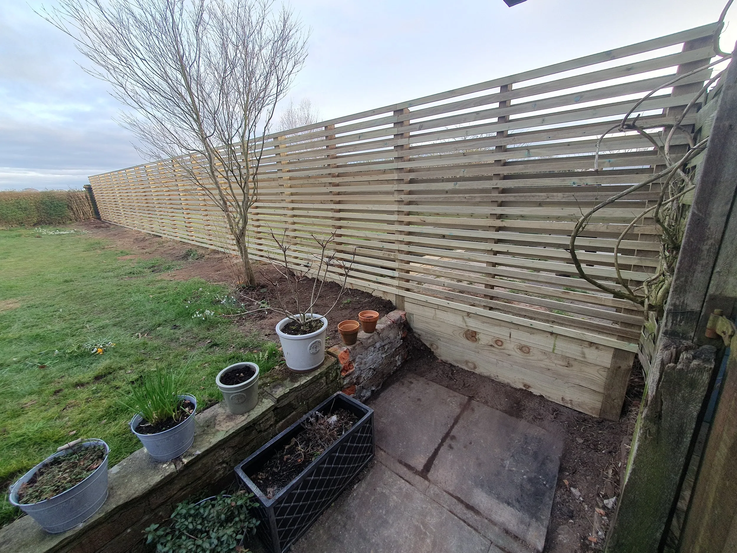A wooden fence with pots of plants on top of it.