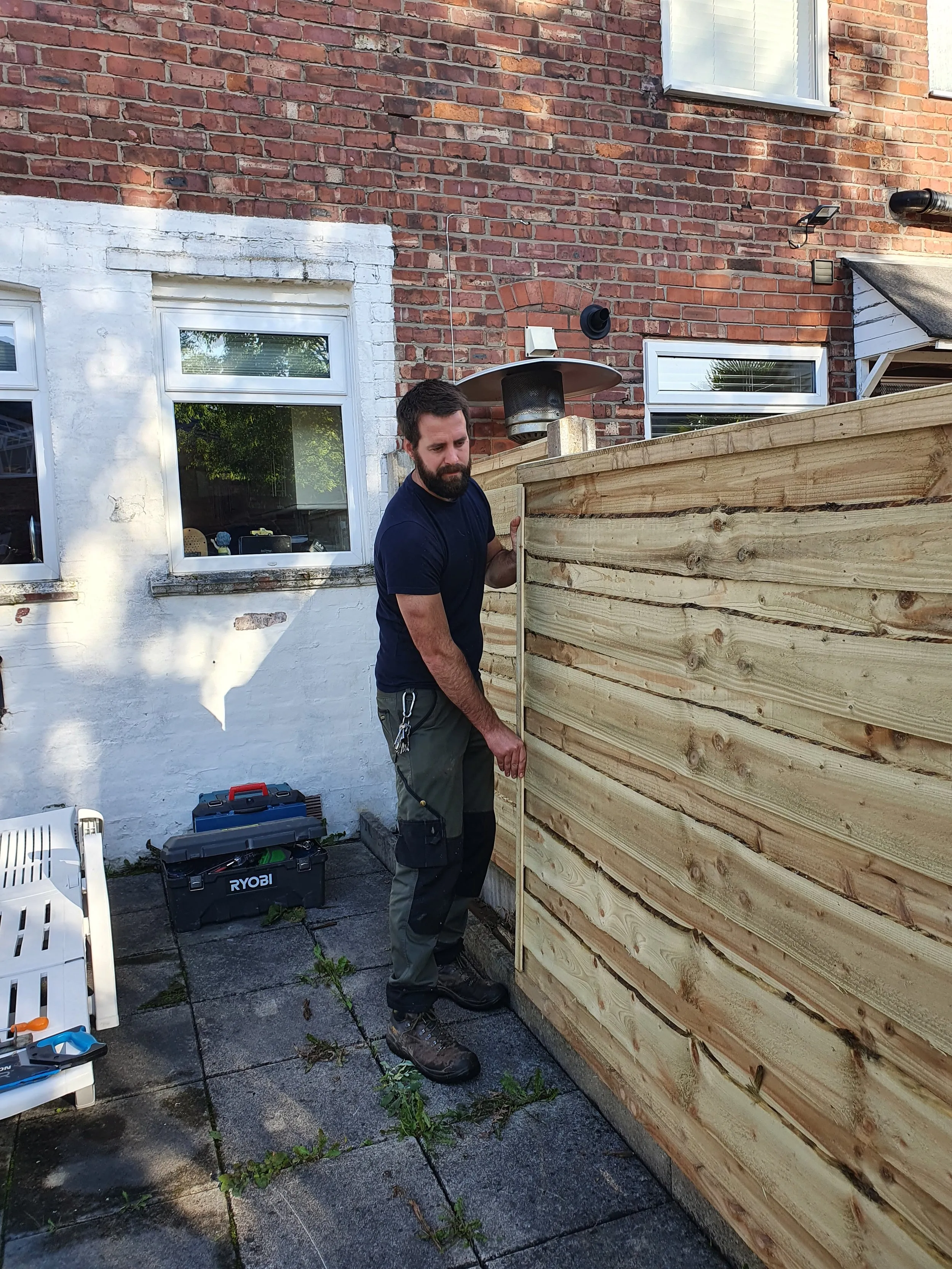 A man standing next to a wooden fence.