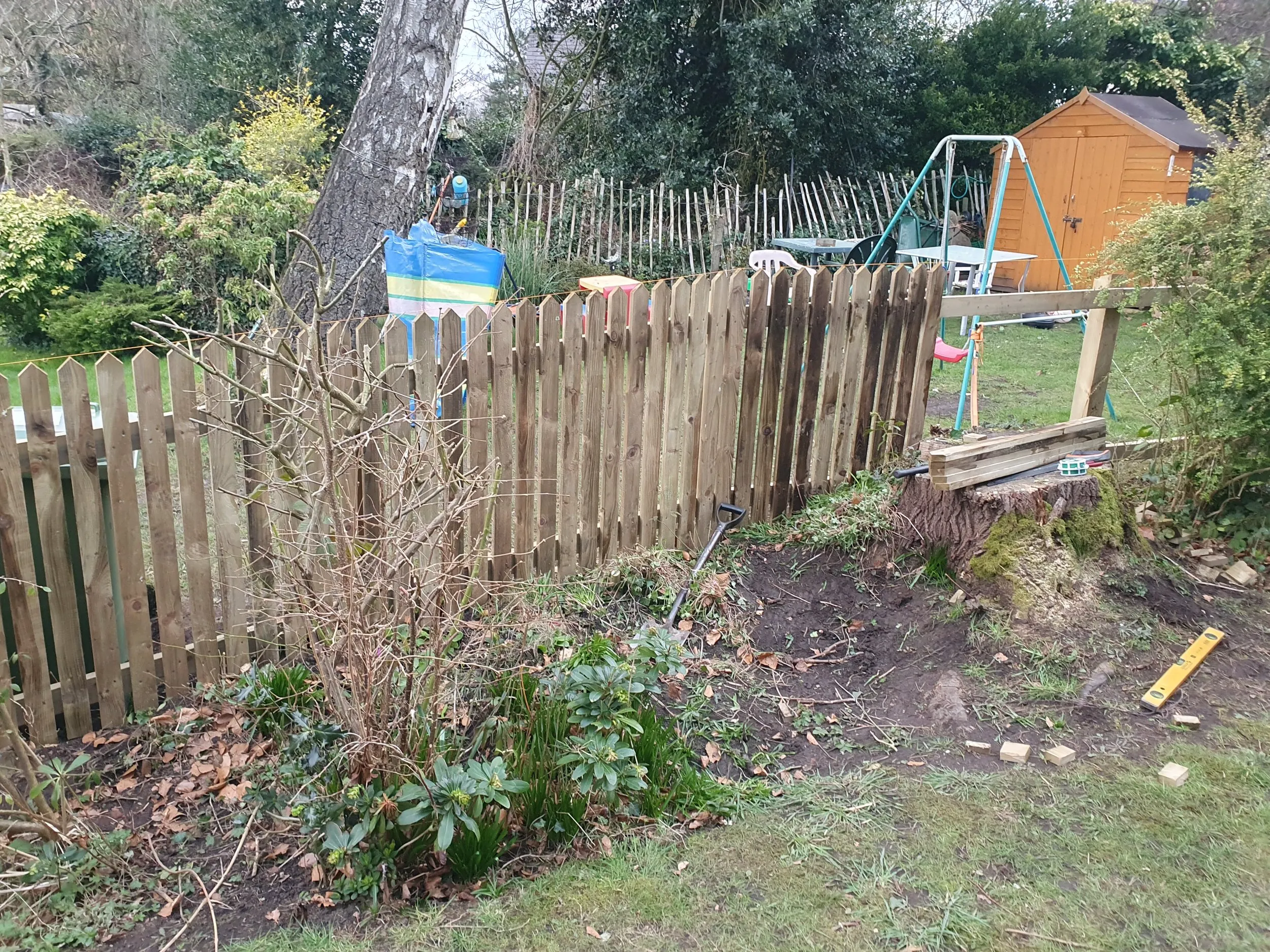 A wooden fence in a yard next to a tree.