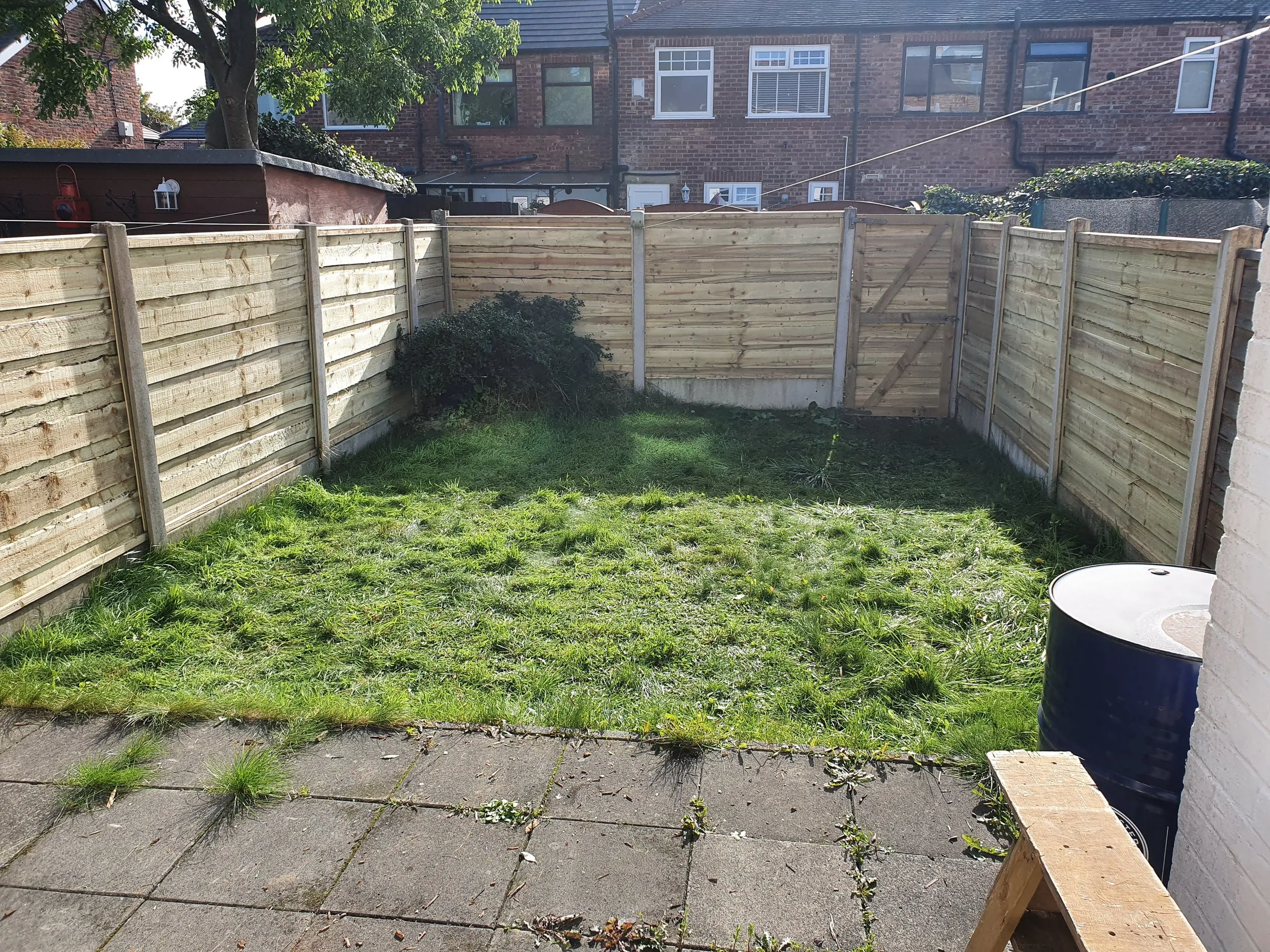 A back yard with a fence and grass.